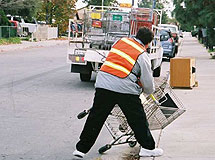 City worker retrieving a shopping cart from the street.